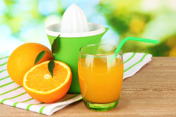 Citrus press, glass of juice and ripe oranges