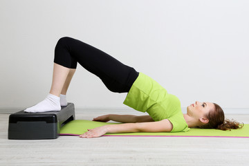 Beautiful young woman exercises on stepper