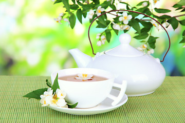 Cup of tea with jasmine, on bamboo mat, on bright background
