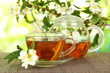 Cup of tea with jasmine, on bamboo mat, on bright background