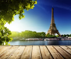 Wandaufkleber Hintergrund mit Holzdecktisch und Eiffelturm in Paris © Iakov Kalinin