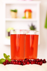 Glasses of cranberry juice and ripe red cranberries on table