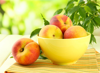 Naklejka na ściany i meble Ripe sweet peaches on table in bowl, outdoors