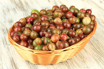 Fresh gooseberries in wicker basket on table close-up