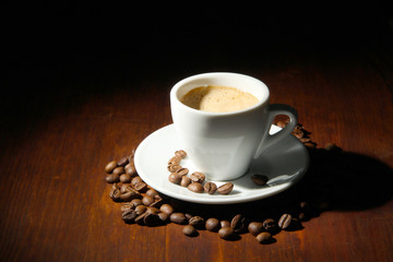 Cup of coffee with coffee beans on wooden background