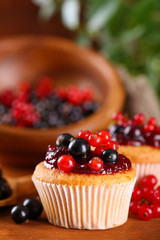 Tasty muffins with berries on wooden table
