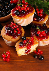 Tasty muffins with berries on wooden table