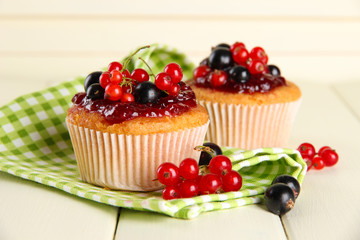 Tasty muffins with berries on white wooden table