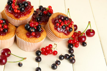 Tasty muffins with berries on white wooden table