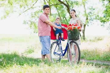 parents carry a child on a bicycle