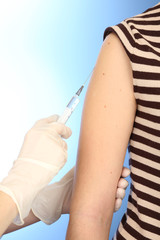 Doctor holding syringe with a vaccine in the patient shoulder,