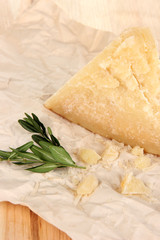 Piece of Parmesan cheese on paper on wooden table close-up