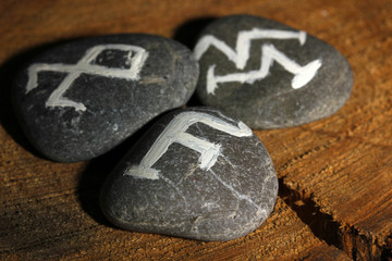Fortune telling  with symbols on stones on wooden background