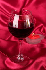 Glass of wine with lipstick imprint on red fabric background