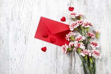 Pink carnations, hearts and red envelope isolated on wooden back