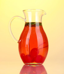 Cherry drink in pitcher on yellow background.