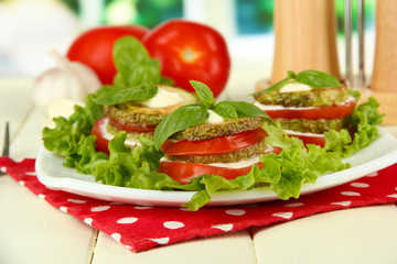 Tasty roasted marrow and tomato slices with salad leaves,