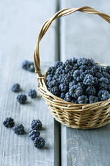 Blackberries in wicker basket on grey wooden table
