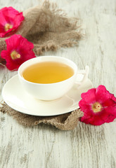 Cup of tea and pink mallow flowers on wooden background