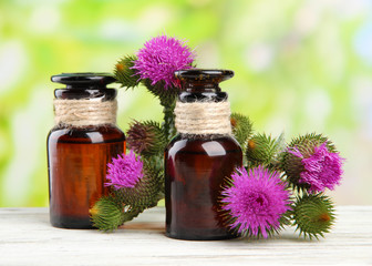 Medicine bottles with thistle flowers on nature background