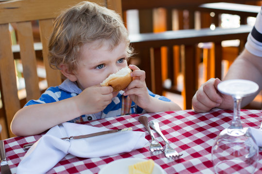 Little toddler boy having breakfast in summer
