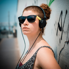 Naklejka premium beautiful stylish modern young woman listening to music
