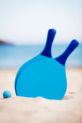Fototapeta na wymiar blaue beachball schläger im sand am meer