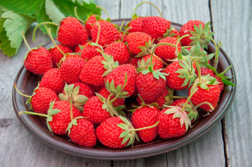 strawberries in ceramic bowl on old wooden background