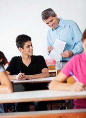 Teacher And Teenage Schoolboy Looking At Paper