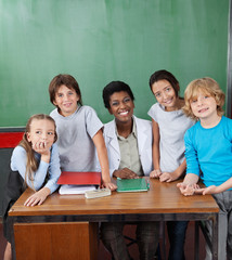 Happy Female Professor With Students At Desk