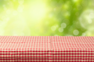 Empty table coved with tablecloth over bokeh garden