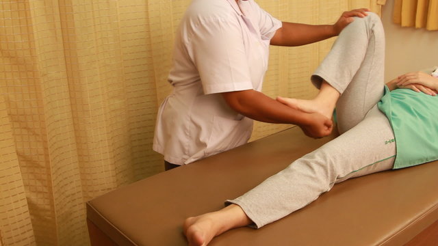 Physiotherapist  examining the leg and knee for her patient