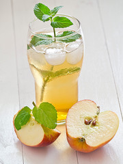 Apfelschorle mit Apfelspalten auf einem weißen Holztablett