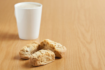 Three rusks with a mug of coffee in the background