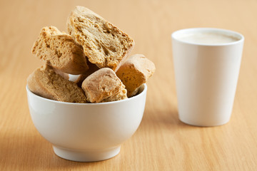 A bowl of rusks with coffee in the background