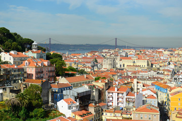 Fototapeta na wymiar 25 de Abril Bridge and Alfama district in Lisbon, Portugal