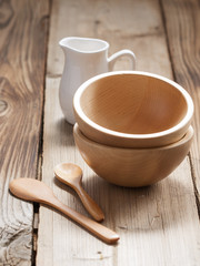 Wooden bowls and a small jug on the wooden background