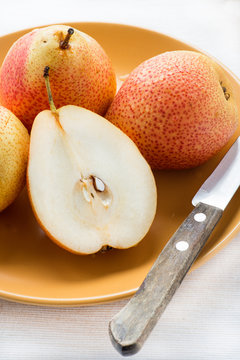 Fresh red pears on plate over light background