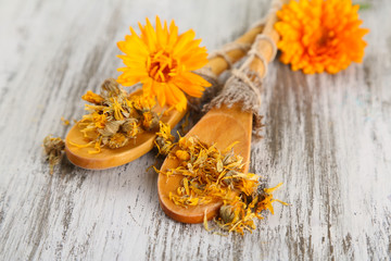 Fresh and dried calendula flowers on wooden background