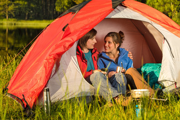 Camping teenagers sitting and embracing in tent