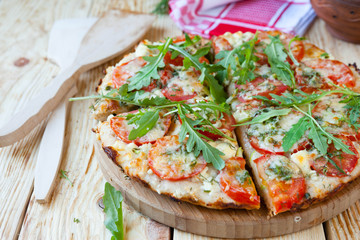 homemade pizza with tomatoes, cheese and arugula