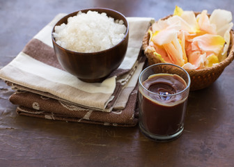 Spa products. Sea salt in bowl with candle and petals on wooden