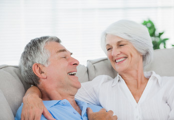 Fototapeta premium Couple laughing and chatting on a couch