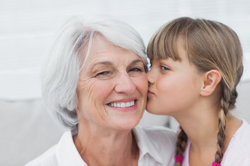 Cute little girl kissing her grandmother