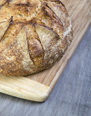 Fresh baked round loaf of sour dough bread on cutting board