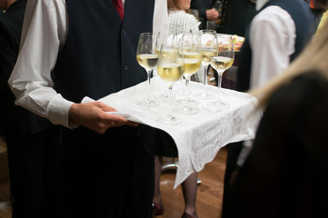 waiter carrying tray with wine glasses