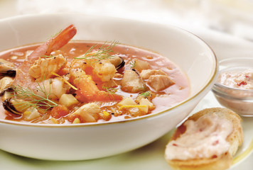 fish soup served on a plate with prawns and mussel