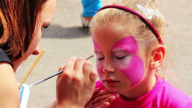 artist paints on face of little girl
