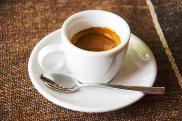 Cup of espresso over brown tablecloth