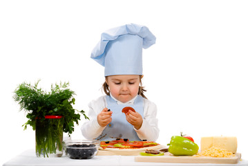 little girl preparing a pizza with salami and vegetables